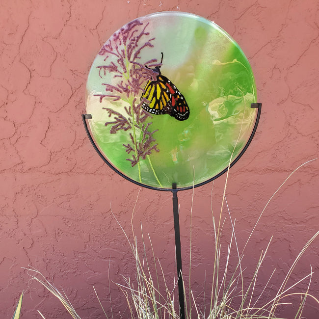 A butterfly sips nectar from penstemon blooms on a glass garden stake